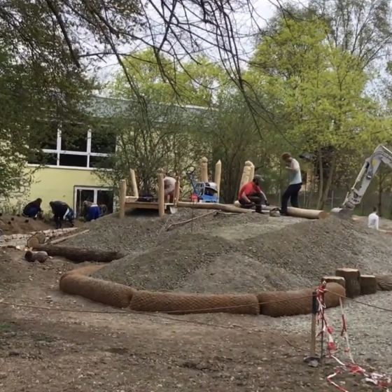 Das Anlegen des neuen Gartens: Aufnahme mit Baggern und Kindern, die bei den Arbeiten helfen