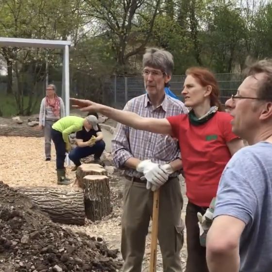 Bauarbeiten in unserem Schulgarten: drei Personen besprechen sich auf der Baustelle