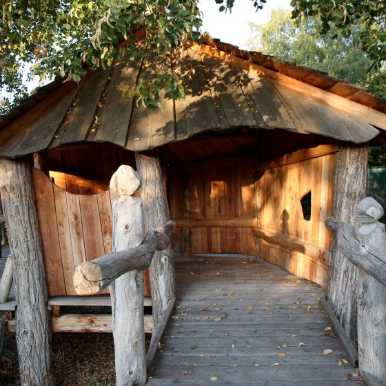 Unser Holzhaus im Garten der Schule mit Brücke und abendlichem Licht im Inneren in herbstlicher Stimmung