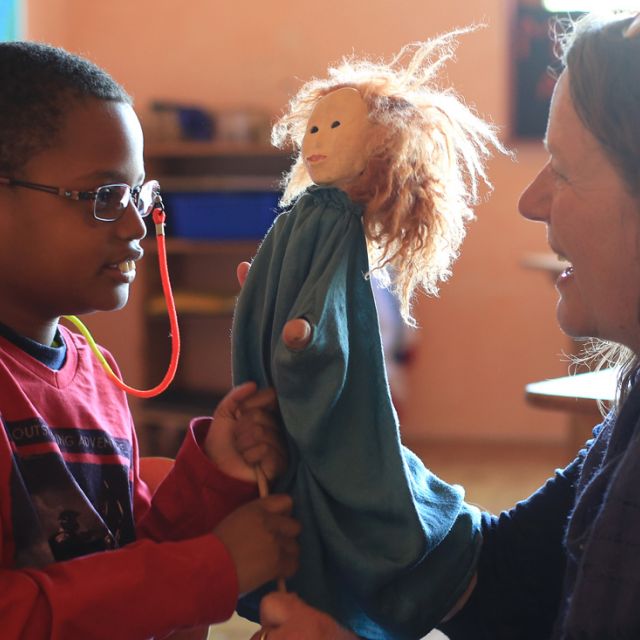 Puppenspiel zwischen Lehrerin und Jungem mit Handpuppe