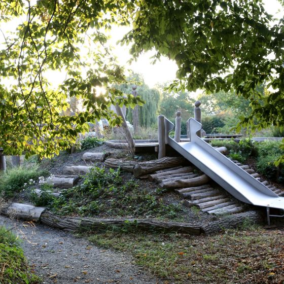 Rutsche in unserem Schulgarten, umrandet von Bäumen